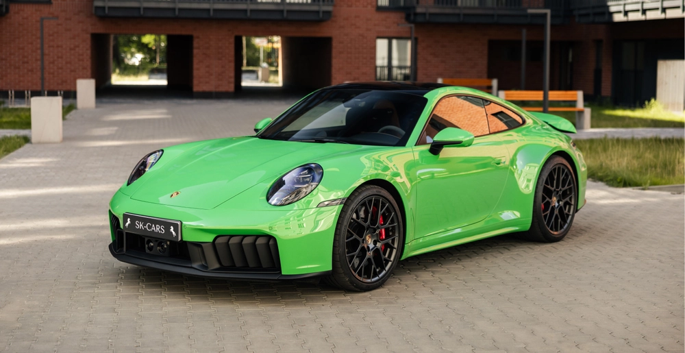 Porsche 911 Carrera GTS in Python Green parked outside a modern residential building