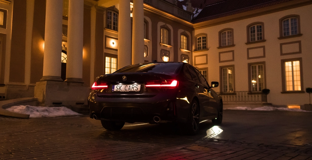 BMW 3 Series na tle luksusowego budynku wieczorową porą — połączenie elegancji i stylu. Zarezerwuj na stronie SK Cars.