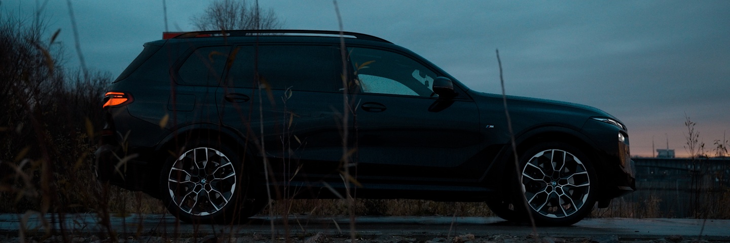 BMW X7 xDrive 40 w czarnym kolorze, widok z profilu o zachodzie słońca – luksusowy SUV do wynajęcia w Warszawie (SK CARS).