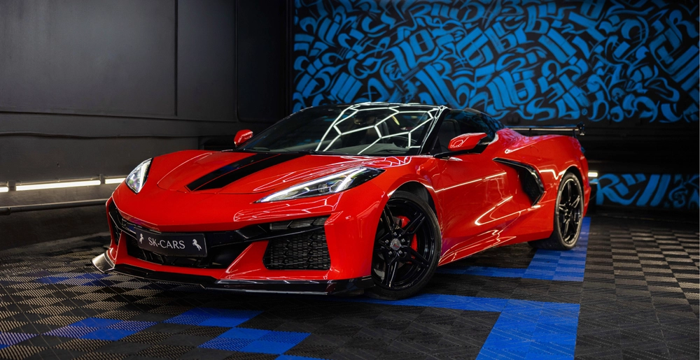 Czerwony Chevrolet Corvette C8 Stingray Cabrio z otwartym dachem i czarnymi elementami nadwozia, widok z przodu.