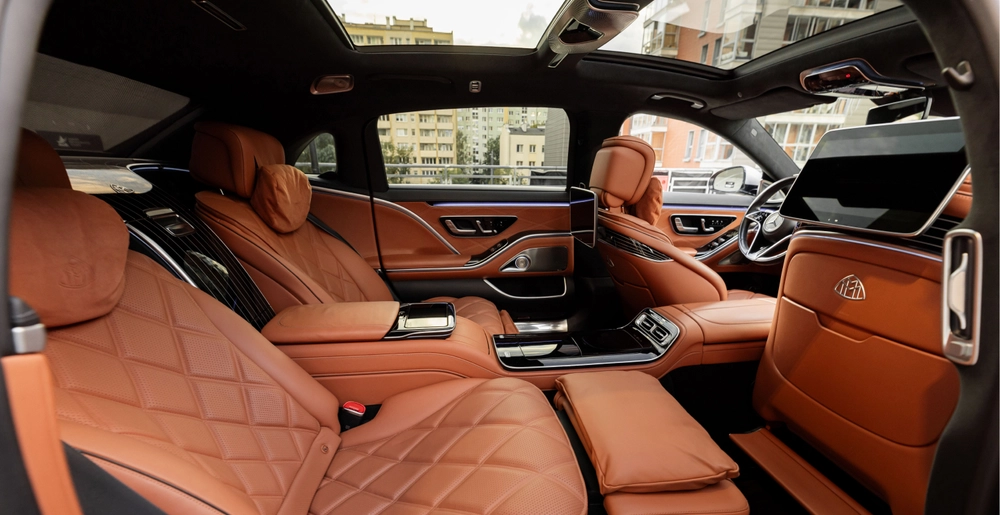 Tylna część wnętrza Mercedes-Maybach S580 ze skórzanymi fotelami, ekranami i panoramicznym dachem