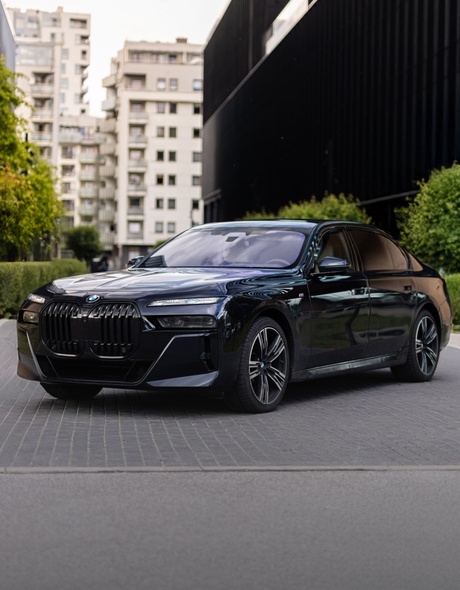 BMW 740d xDrive – luksusowa limuzyna na tle nowoczesnej architektury Warszawy. Dostępna do wynajęcia w SK CARS – samochody premium bez kompromisów.