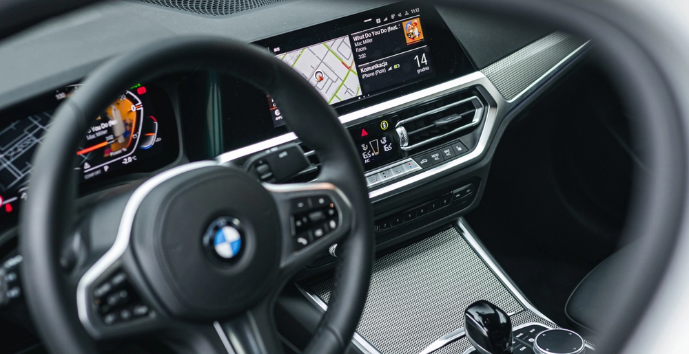 Wnętrze BMW 3 Series z cyfrowym wyświetlaczem i systemem nawigacji. Wygodna obsługa i stylowy design dostępne w wynajmie w SK CARS.