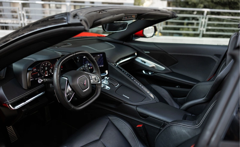 Czarne skórzane wnętrze Chevrolet Corvette C8 Stingray Cabrio z otwartym dachem, sportowymi fotelami i cyfrowym kokpitem.