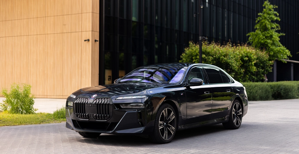 BMW 740d xDrive – luxury sedan with bold front view in modern Warsaw setting. Available for rent at SK CARS – premium cars, unforgettable experience.