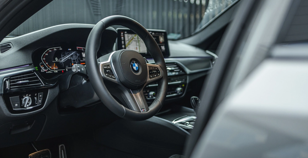 Роскошный салон BMW 5 серии с современным рулевым управлением и цифровой панелью приборов. Идеальное сочетание стиля и комфорта в аренду от SK CARS.