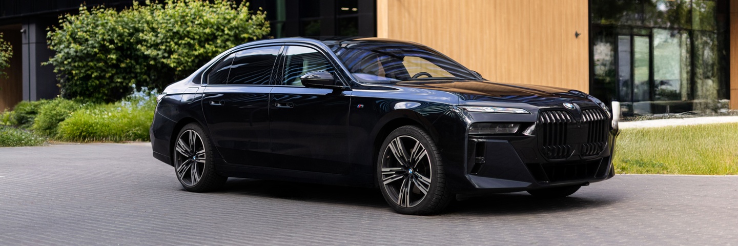 BMW 740d xDrive – nowa generacja limuzyny klasy premium z pakietem M, elegancki czarny kolor, zdjęcie w miejskim krajobrazie Warszawy. Auto do wynajęcia w SK CARS.