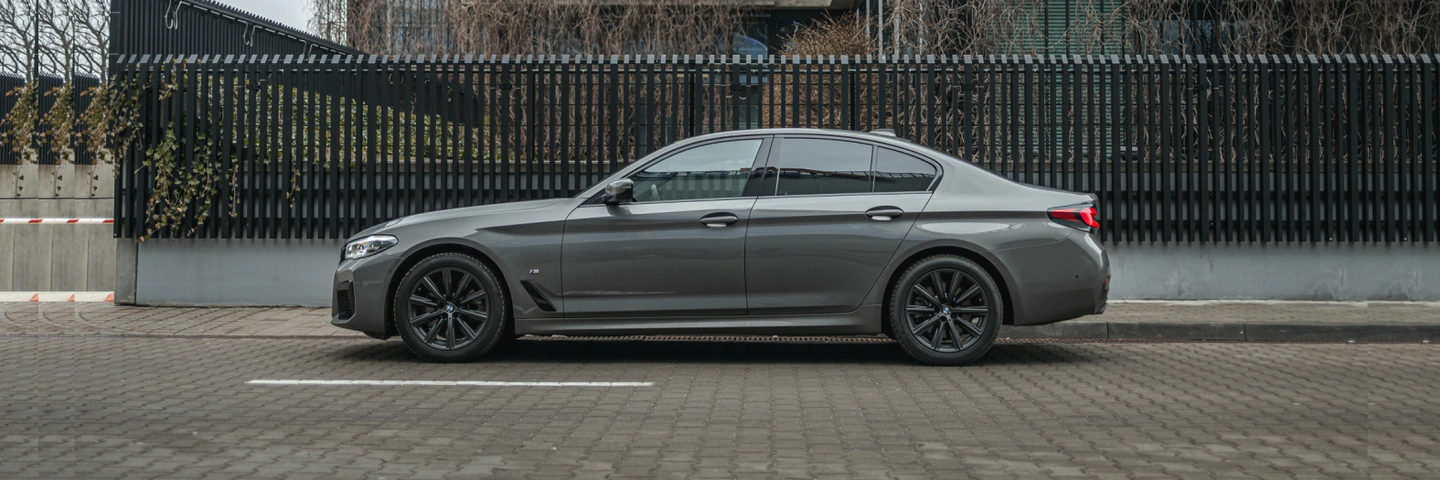 Side view of a gray BMW 5 Series showcasing elegance and power. Reserve this car at SK CARS for a unique driving experience.