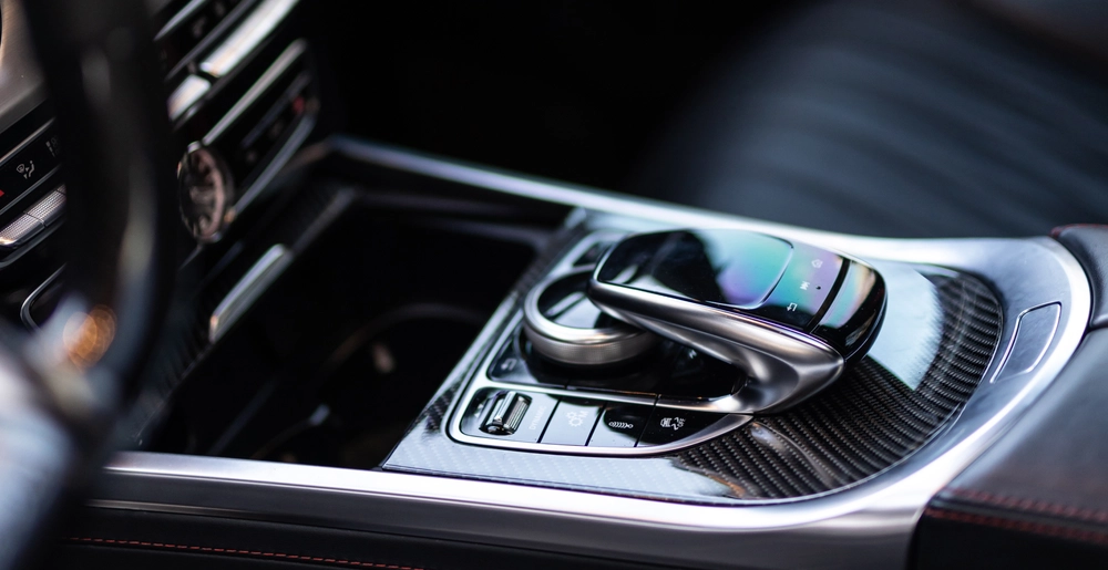 Центральная консоль Mercedes-AMG с карбоновыми вставками, тачпадом и элементами управления мультимедиа и функциями автомобиля.