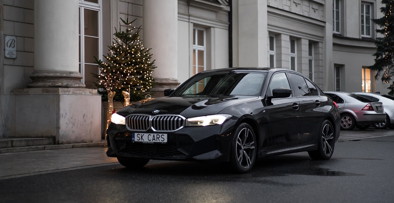 Elegancki BMW Series 3 przed świątecznie ozdobionym hotelem, podkreślający luksus i wygodę wynajmu z SK Cars.