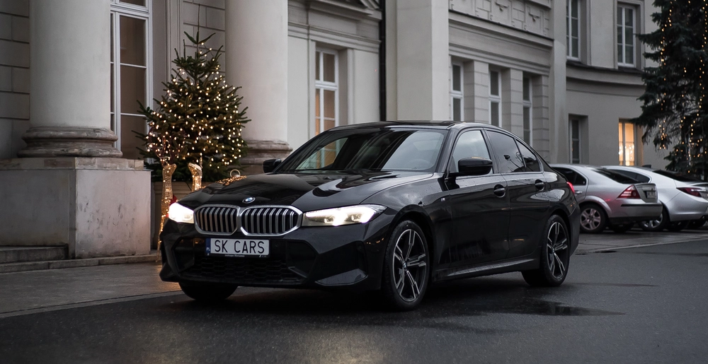 Elegancki BMW Series 3 przed świątecznie ozdobionym hotelem, podkreślający luksus i wygodę wynajmu z SK Cars.