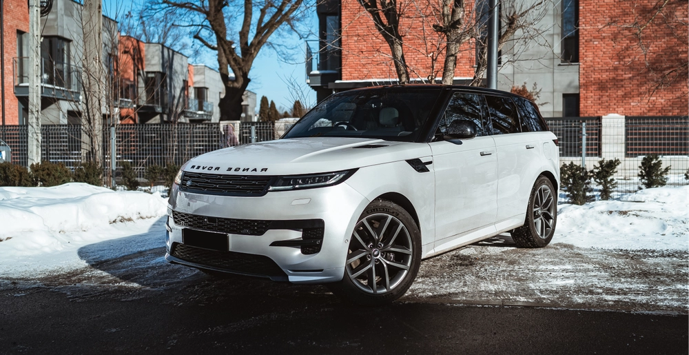 Белый Range Rover Sport на улице в Варшаве, вид спереди слева, аренда премиального внедорожника SK CARS.