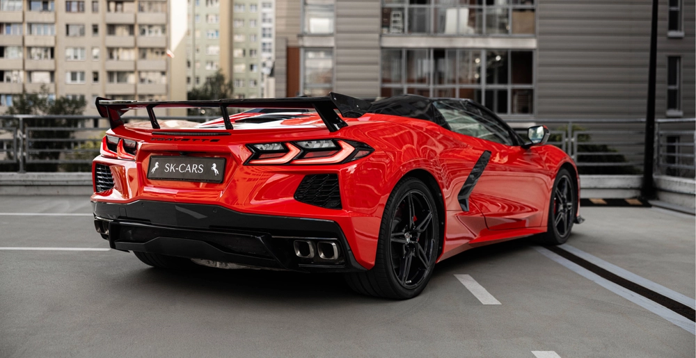 Czerwony Chevrolet Corvette C8 Stingray Cabrio, widok z tyłu pod kątem, z dużym spojlerem i czterema końcówkami wydechu.