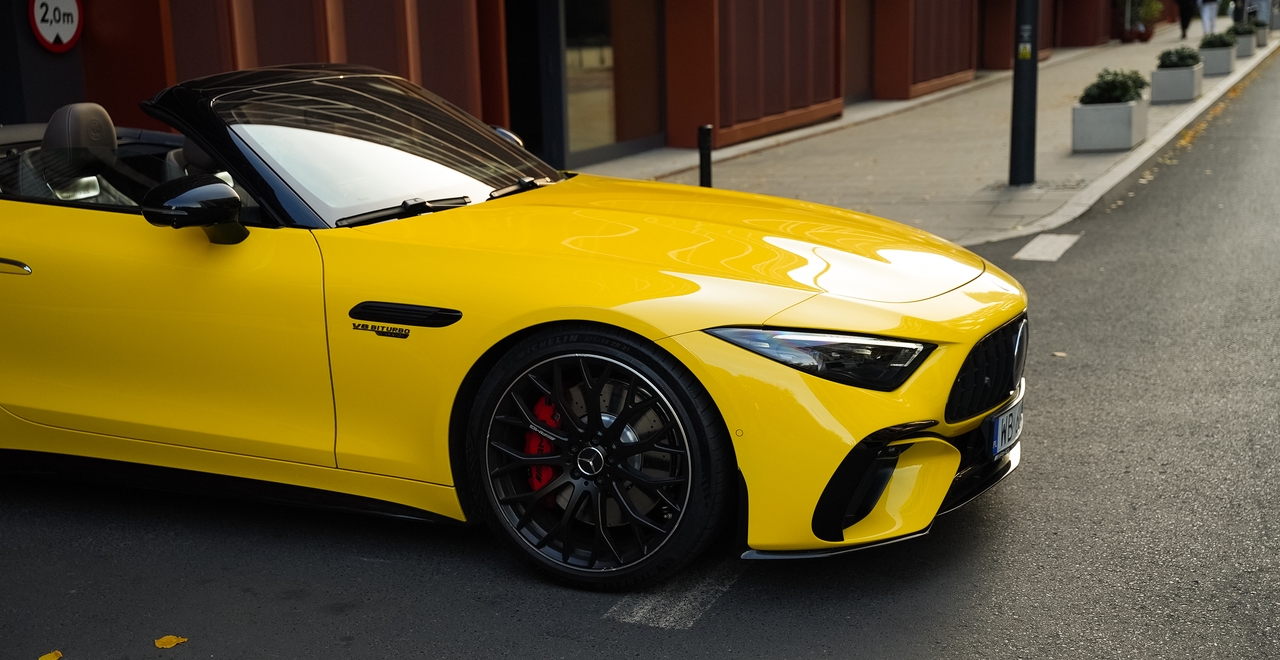 Mercedes SL55 AMG — yellow convertible, front side view with red brake calipers and V8 Biturbo badge