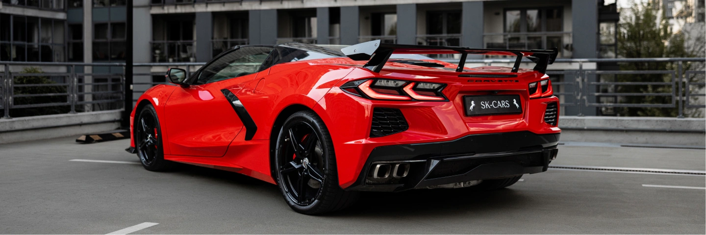 Czerwony Chevrolet Corvette C8 Stingray Cabrio z otwartym dachem, widok z tyłu pod kątem, wynajem samochodu sportowego w Warszawie.