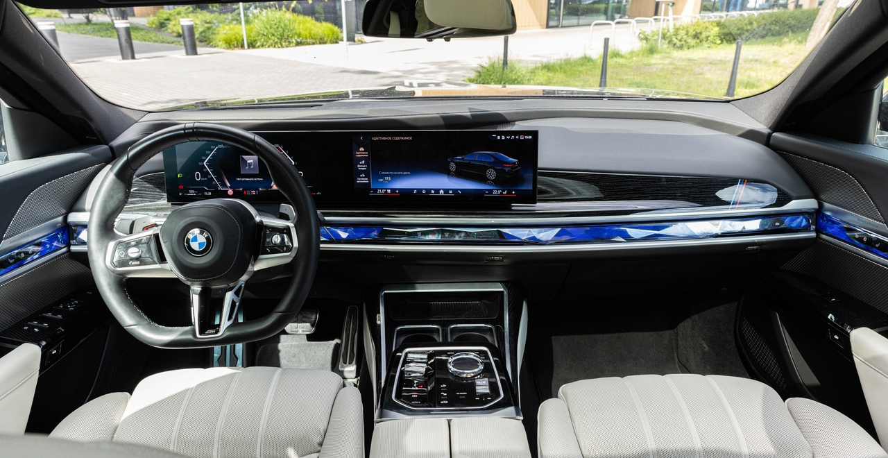 Luksusowe wnętrze BMW 740d xDrive M Sport – cyfrowy kokpit, kryształowy wybierak biegów i niebieskie podświetlenie ambientowe. Dostępne w wynajmie w SK CARS Warszawa.