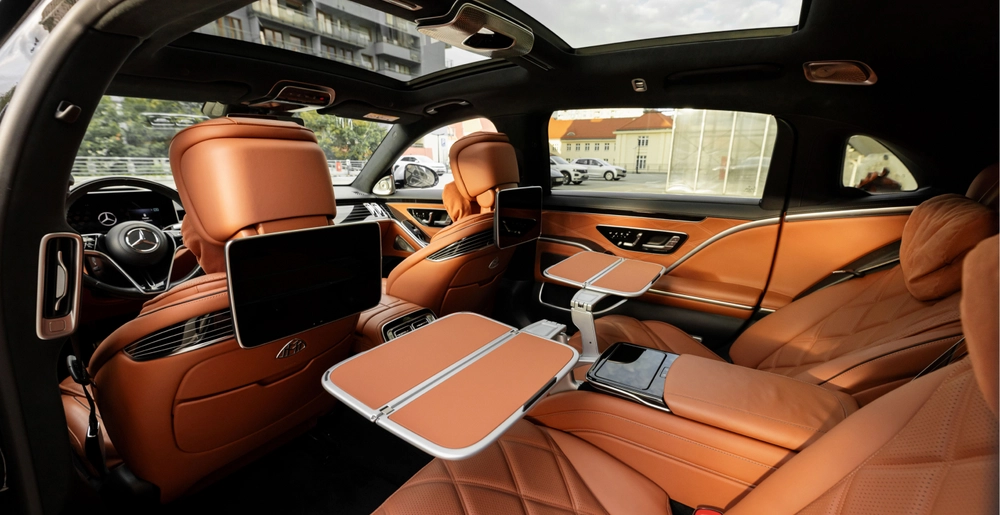Luksusowe brązowe wnętrze Mercedes-Maybach S580 z tylnymi fotelami, stolikami i ekranami
